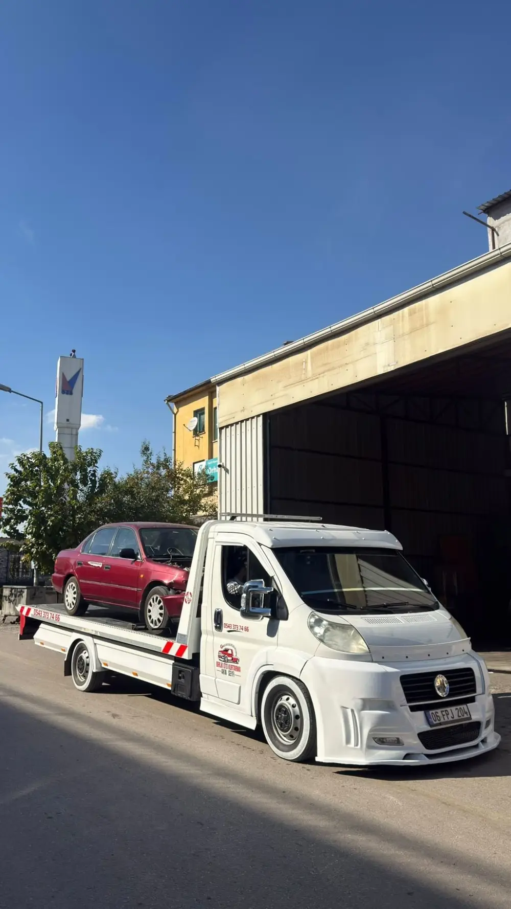 Ön kısmı hasarlı kırmızı bir sedan, Birlik Oto Kurtarma çekicisinin kasasında servis önünde