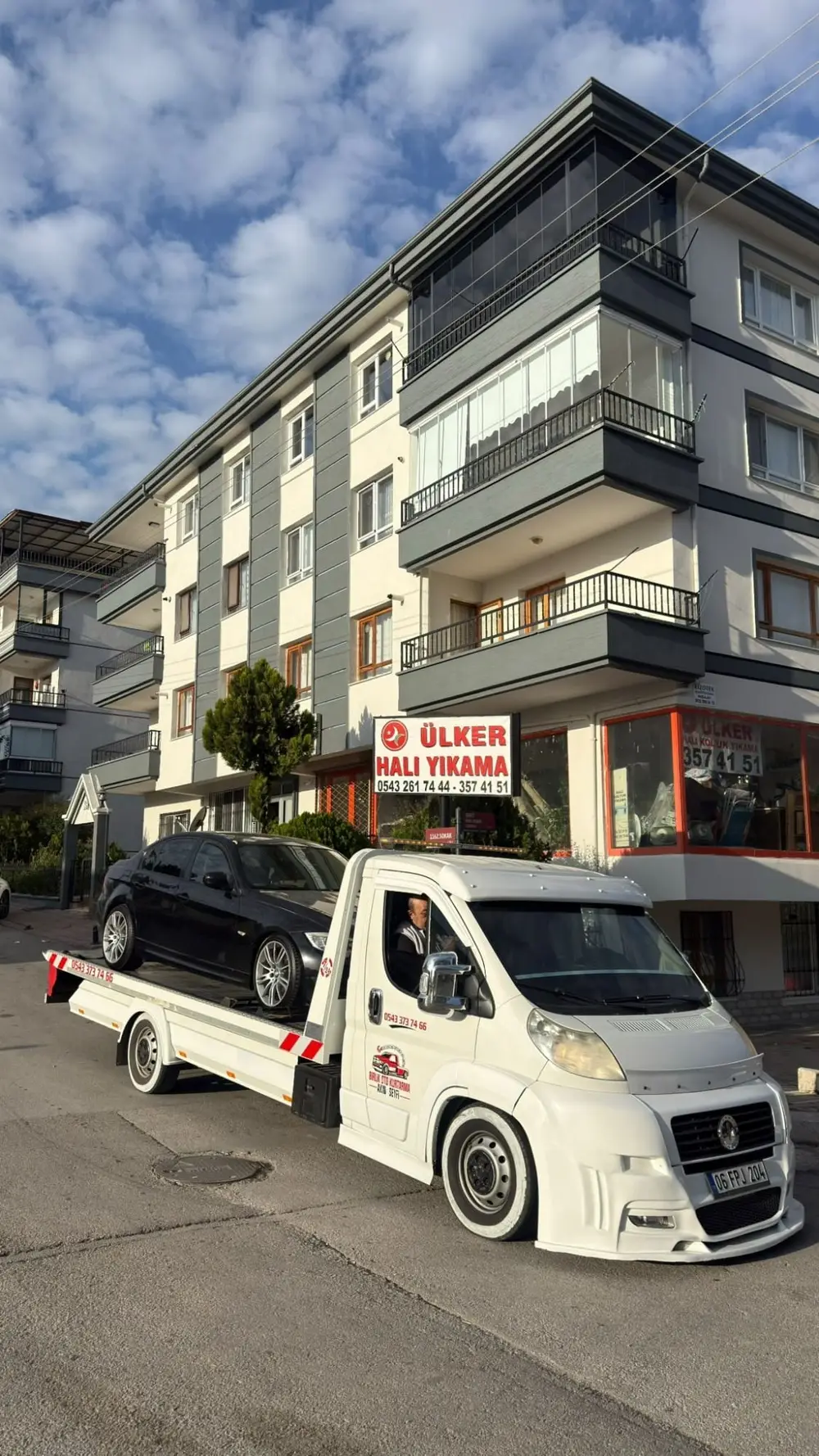 Birlik Oto Kurtarma çekicisi kasasında siyah bir sedan, apartman önünde